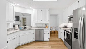 A modern kitchen with white cabinets, a dishwasher, a refrigerator, an oven, and a microwave. - Renovated 3BR Retreat With Game Room (Montgomery)