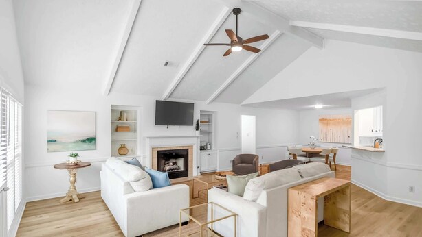 A spacious loft-style living area with a fireplace, white sofas, a TV, and a ceiling fan. - Renovated 3BR Retreat With Game Room (Montgomery)