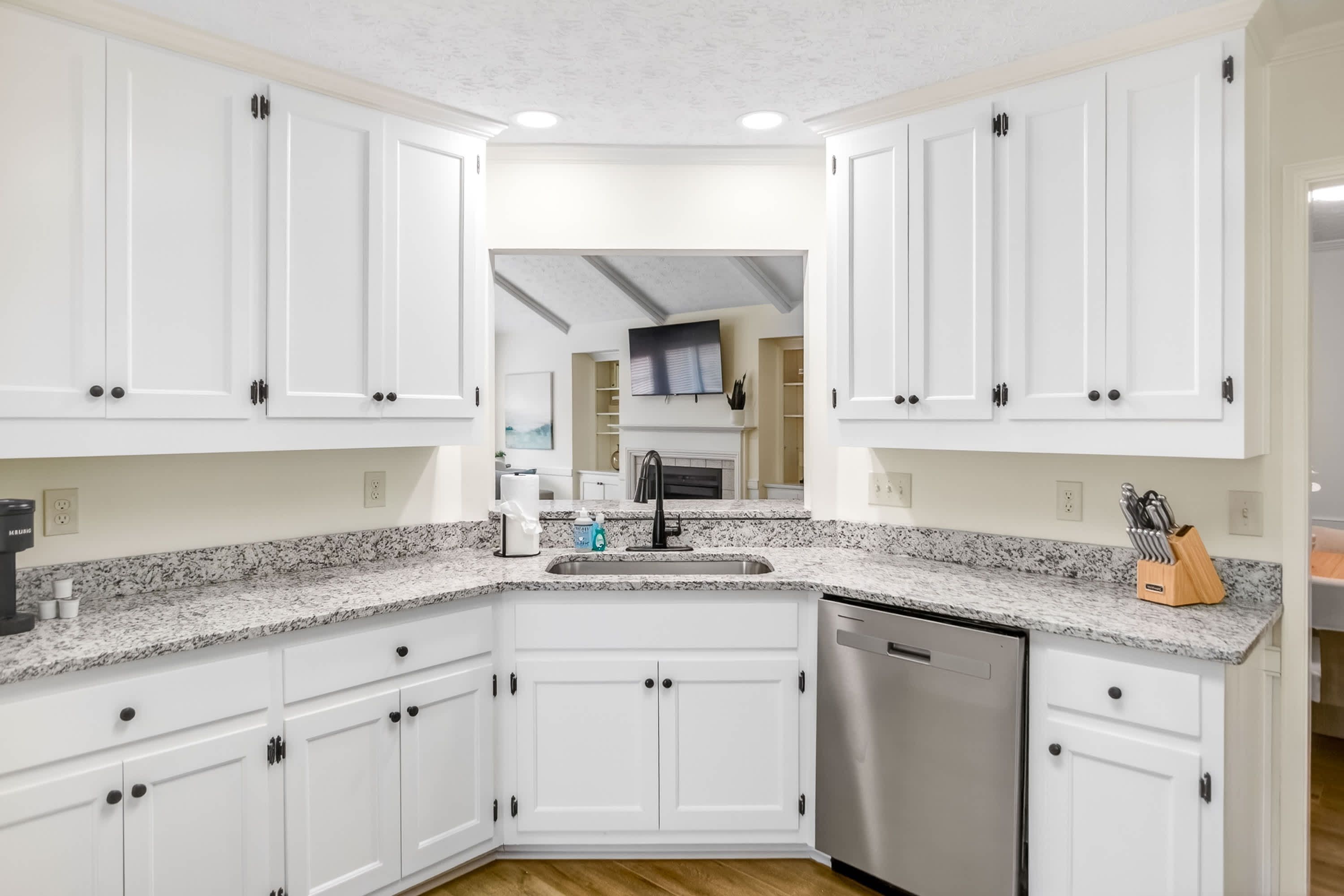 A kitchen with white cabinets, granite countertops, a stainless steel dishwasher, and a built-in oven.