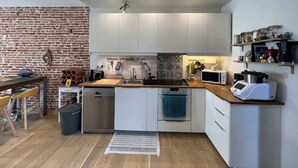 Cozinha compacta com armários brancos, bancada de madeira, micro-ondas e pia.