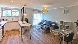 A modern kitchen with a dining area, a sofa, and a small table. - Colocation Meubl e Ar nes Bail Individuel (Toulouse)