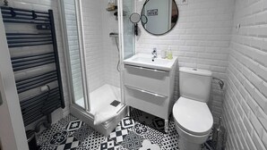 A bathroom with a glass-enclosed shower, a white sink with a mirror, and a toilet. - The Manhattan - 2p- Over Toulouse s Roofs (Toulouse)