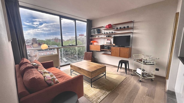 A modern living room with a sofa, a coffee table, a TV, and a dining area with a small table and chairs. - The Manhattan - 2p- Over Toulouse s Roofs (Toulouse)