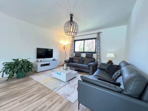 A modern living room with a flat-screen TV, a leather sofa, a coffee table, and a potted plant. - The Coteau - 8p - Pool - Toulouse s Countryland (Balma)