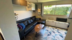 Ett modernt vardagsrum med en svart lädersoffa, ett soffbord och en matta med geometriskt mönster.