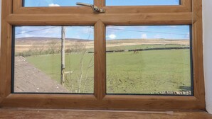A window with a view of a green field and a distant hill. - 1 Upper Austby Farm Cottage (Ilkley)
