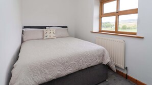A bedroom with a bed, a window, and a radiator. - 1 Upper Austby Farm Cottage (Ilkley)
