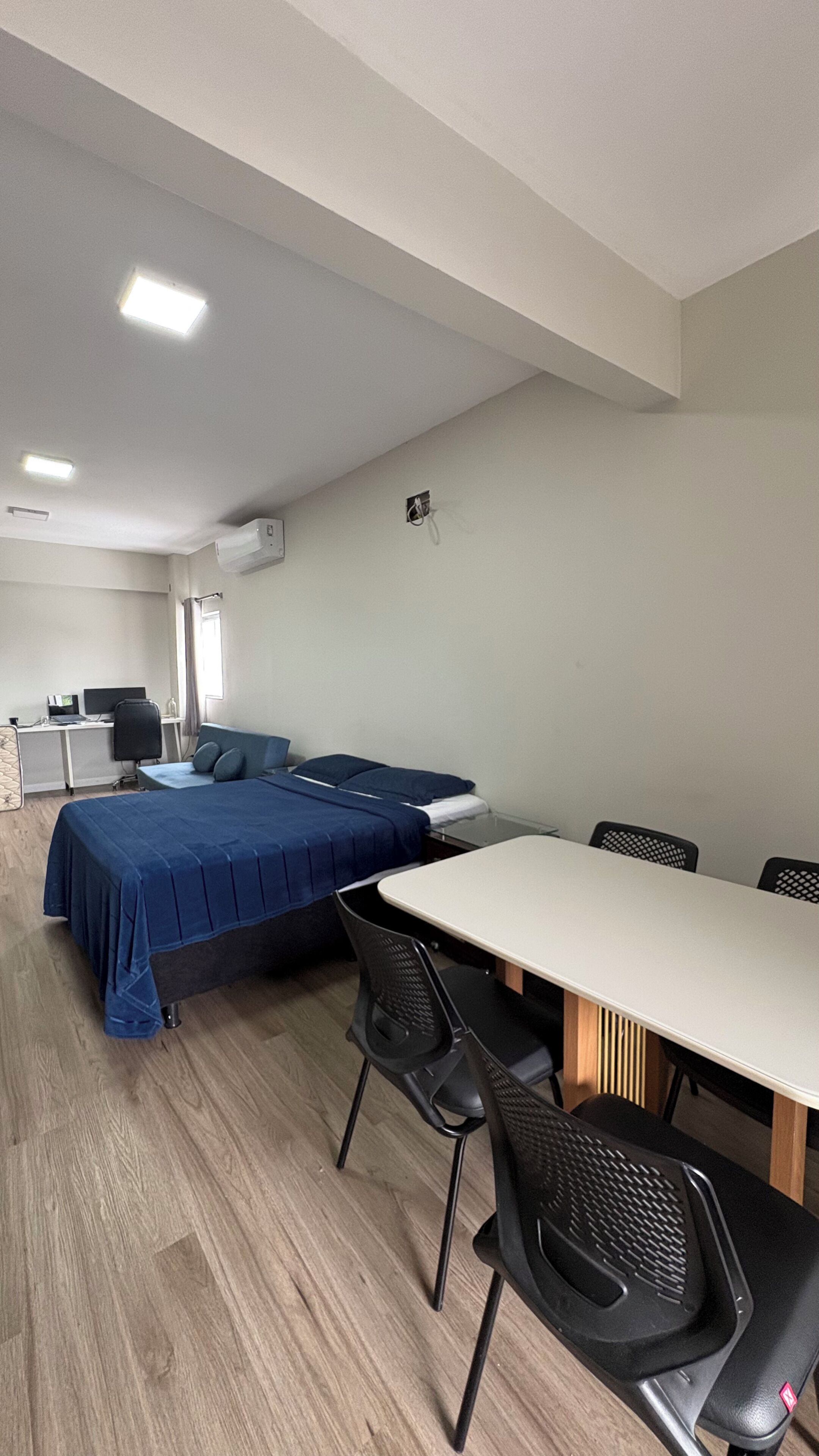 Una habitació amb un llit, escriptori, cadira i taula.