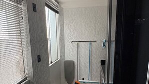 Una cocina moderna con horno empotrado, una ventana con persianas y una puerta que da a otra habitación.