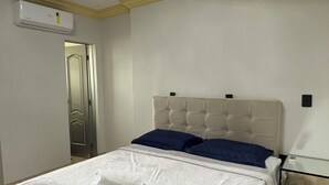 Un dormitorio con cama, mesita de noche y unidad de aire acondicionado.