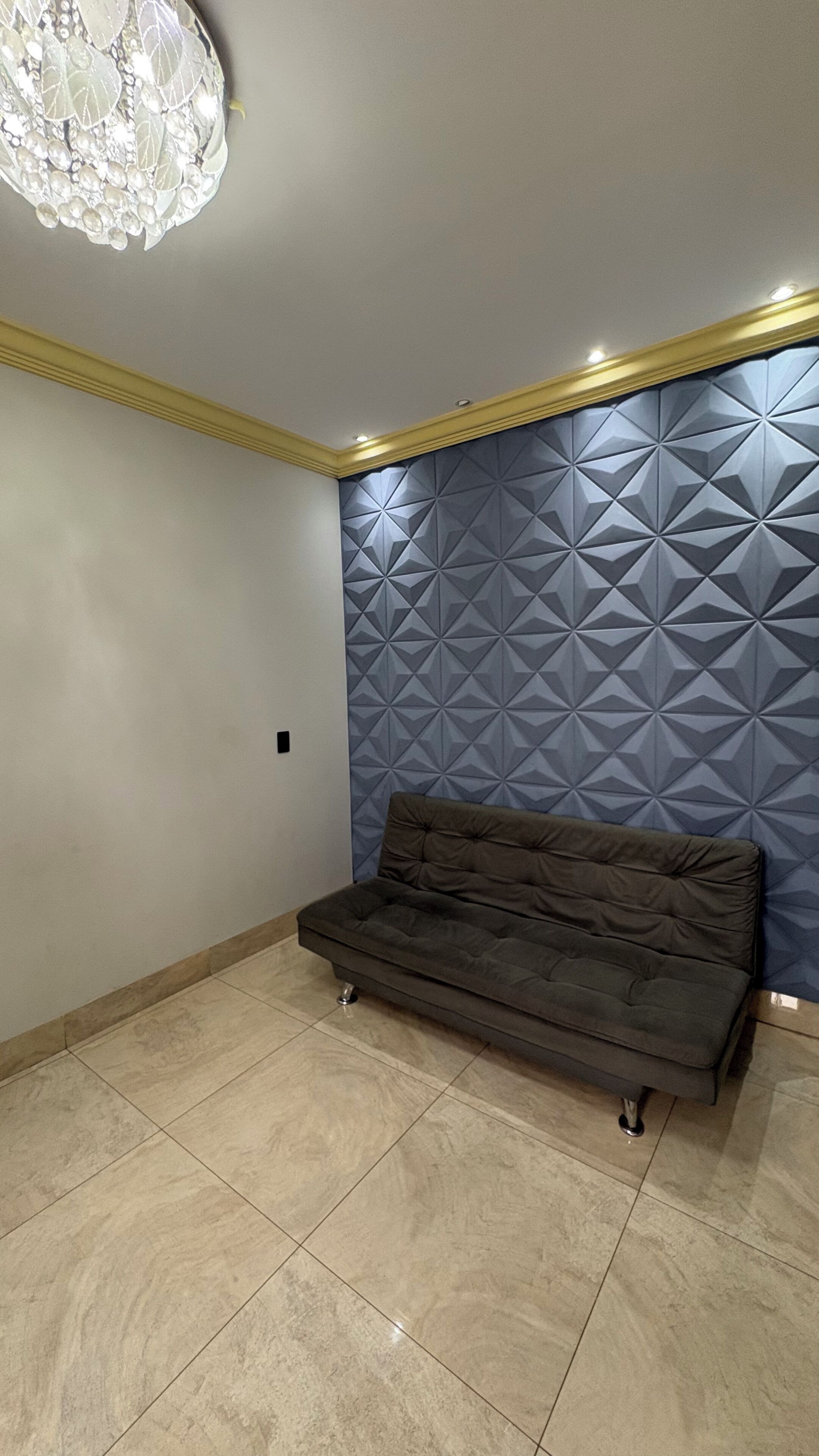 A room with a geometric-patterned wall, a tufted sofa, and a chandelier.
