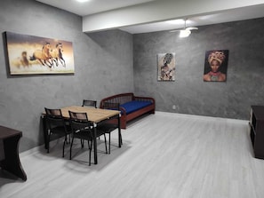 Um quarto com uma mesa de jantar, cadeiras, um sofá e obras de arte nas paredes.