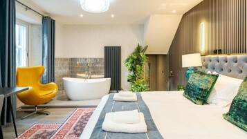 Quarto de hotel moderno com uma cama grande, uma banheira, uma cadeira amarela e um candelabro.