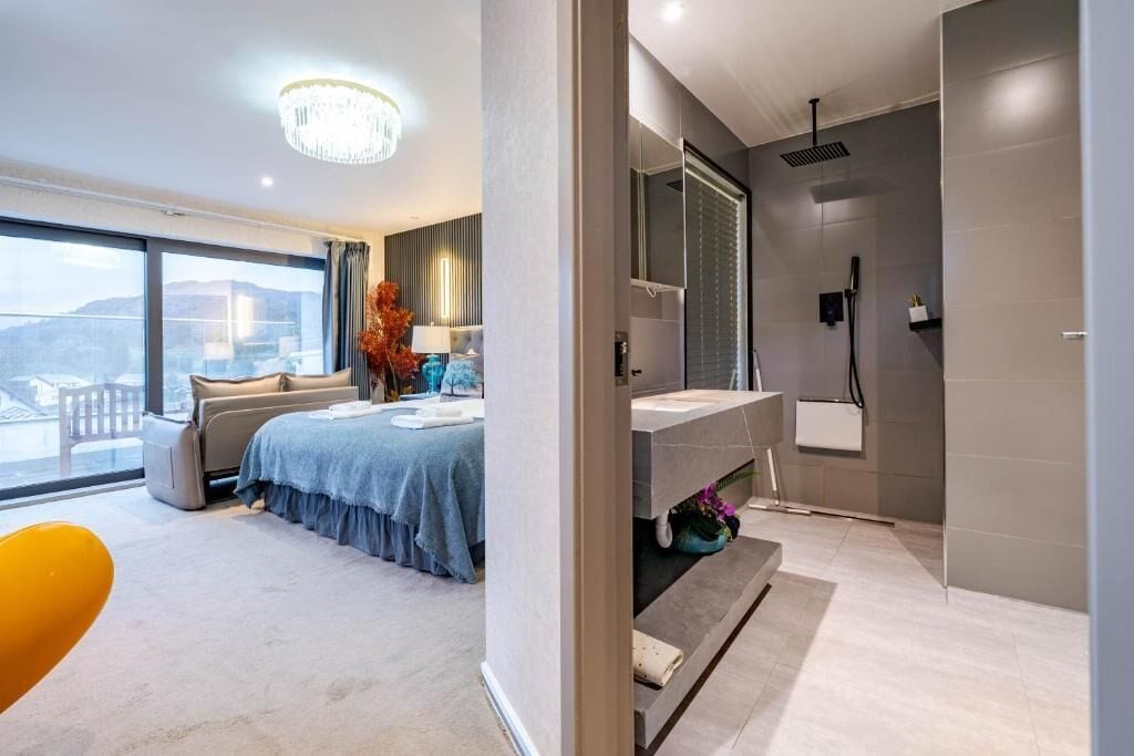 A modern hotel room with a large bed, a bathroom with a shower, and a view of the city.