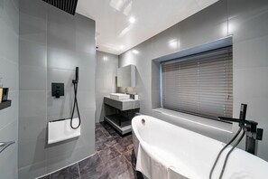 A modern bathroom with a freestanding bathtub, a shower area, and a vanity with a mirror. - Waterhead Bath Suites (Ambleside)