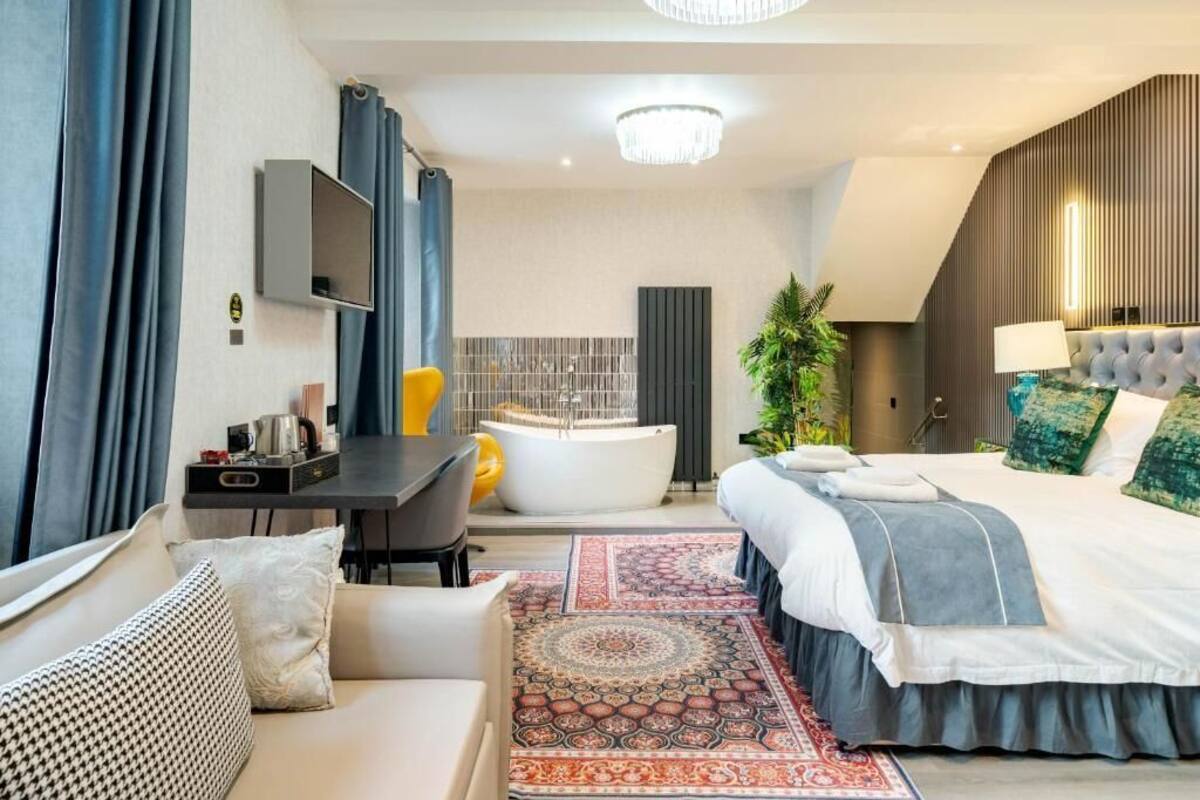 Una habitación de hotel moderna con cama, escritorio, bañera y televisión.
