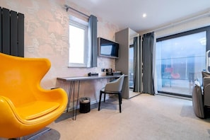A modern room with a yellow chair, a desk, a television, and a large window.