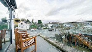 Un balcon donnant sur une rue, un banc en bois et une rambarde en verre.