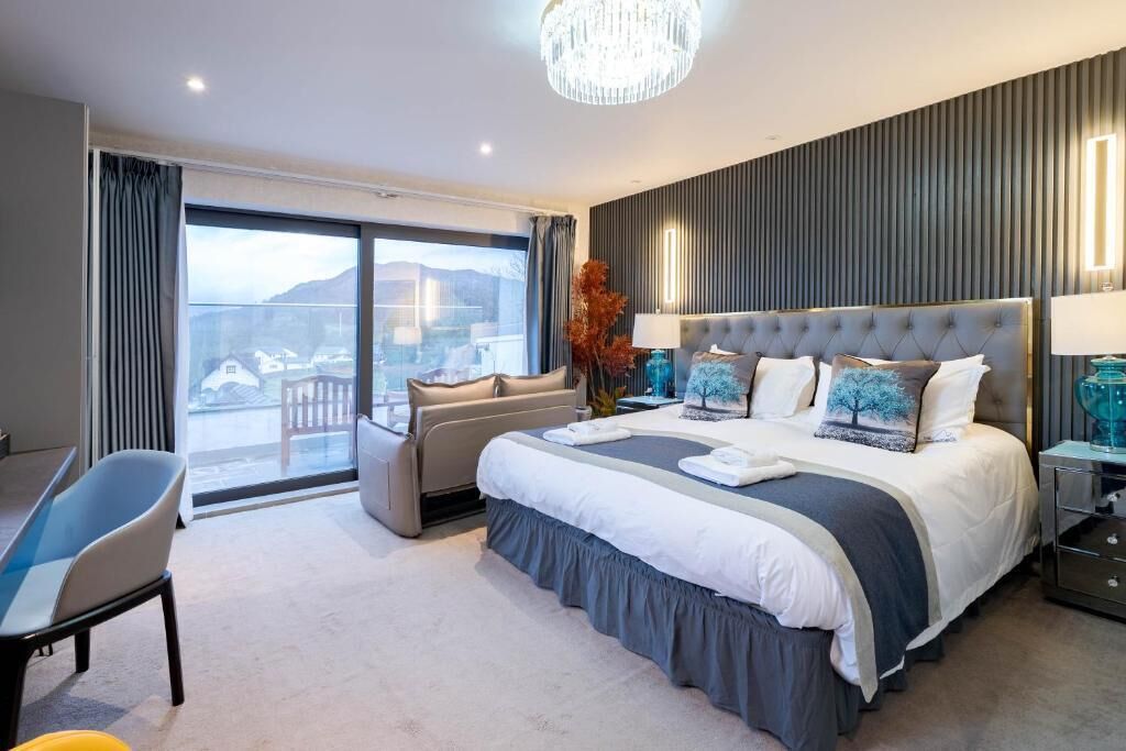 A modern hotel room with a large bed, a seating area, and a view of the outdoors.