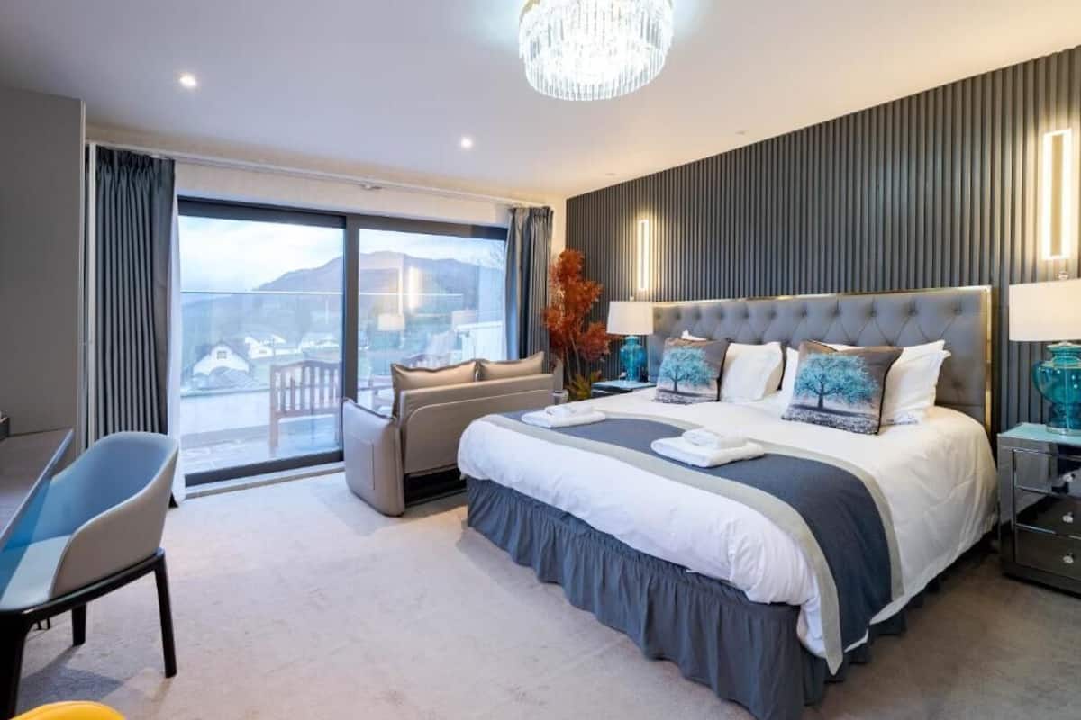 Una habitación de hotel moderna con una cama grande, un área de descanso y vistas al exterior.