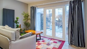 Un salon moderne avec un canapé, une petite table et une grande porte-fenêtre coulissante donnant sur un balcon.