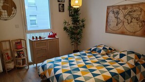 Makuuhuone, jossa on sänky, puinen lipasto, ikkuna, seinällä oleva kartta ja katosta roikkuva valaisin.
