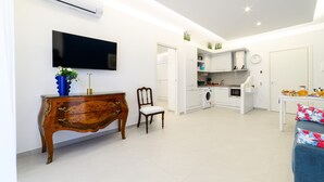 Eine moderne Küche mit weißen Schränken, einem eingebauten Backofen und einem Essbereich mit einem blauen Sofa und einem kleinen Tisch.