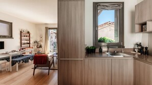 Cocina moderna con armarios de madera, un lavaplatos integrado y una ventana con vistas a edificios.
