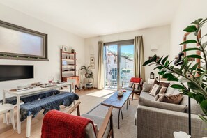 A modern living room with a flat-screen TV, a dining table, a sofa, and a balcony with a view. - Casetta Monti (Brunate)