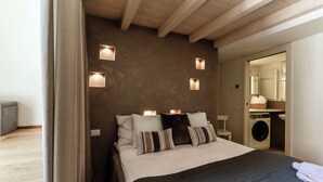 Un dormitorio con cama, mesitas de noche, lavadora y espejo.