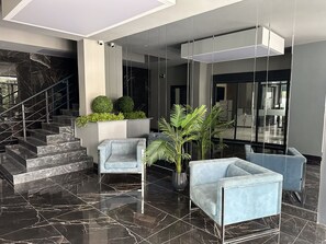 En moderne lobby med marmorgulv, trappe og siddeområder.