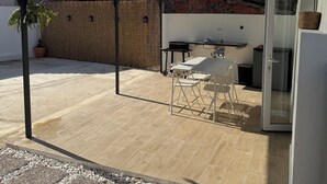 A patio area with a table and chairs, a grill, and a covered seating area.