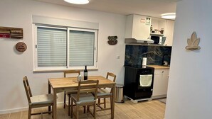 A compact kitchen with a dining table and chairs, a built-in oven, and a window with blinds.