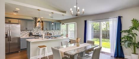 A modern kitchen with a central island, stainless steel appliances, and pendant lighting.
