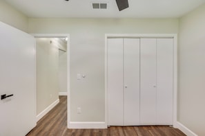A hallway with a white door, a white closet, and a wooden floor.