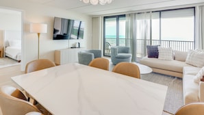 A modern hotel room with a dining area, a sofa, and a balcony with a view. - Stunning Views, Luxe Decor: Suntide III - Unit 805 (South Padre Island)