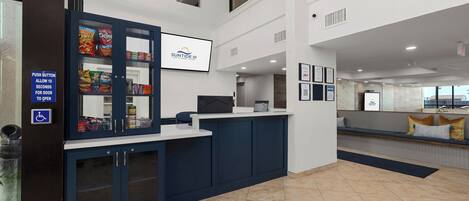 A reception area with a counter, a vending machine, a seating area, and a sign indicating a push button for the door.