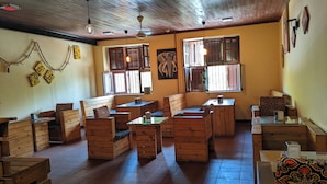 A cozy restaurant with wooden furniture, large windows, and a tiled floor. - The Hub Train House Exotic Roots (Zanzibar Town)