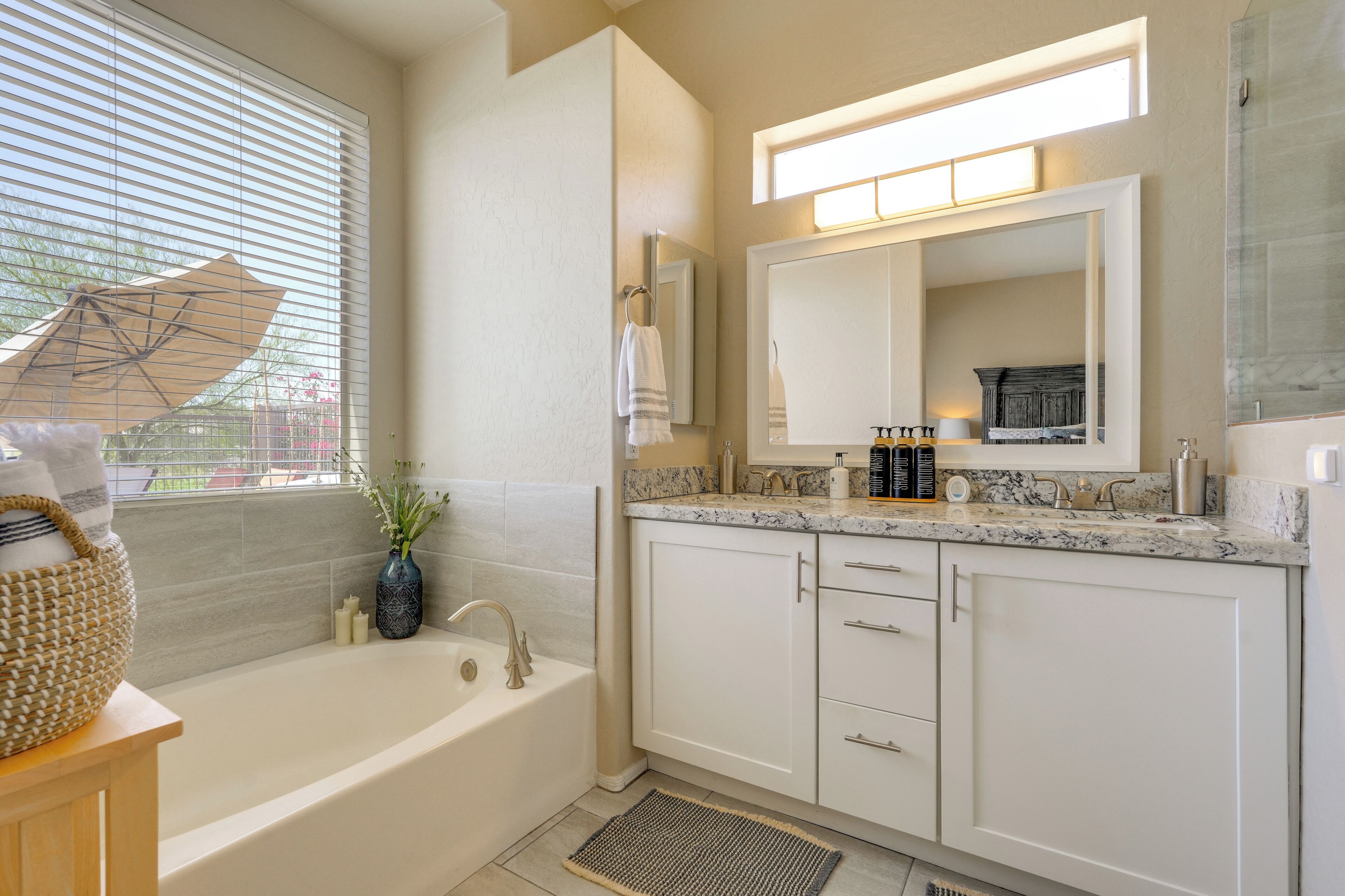 A modern bathroom with a bathtub, vanity, and a large mirror.