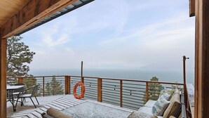 A wooden deck with outdoor furniture, a lifebuoy, and a view of the sea.
