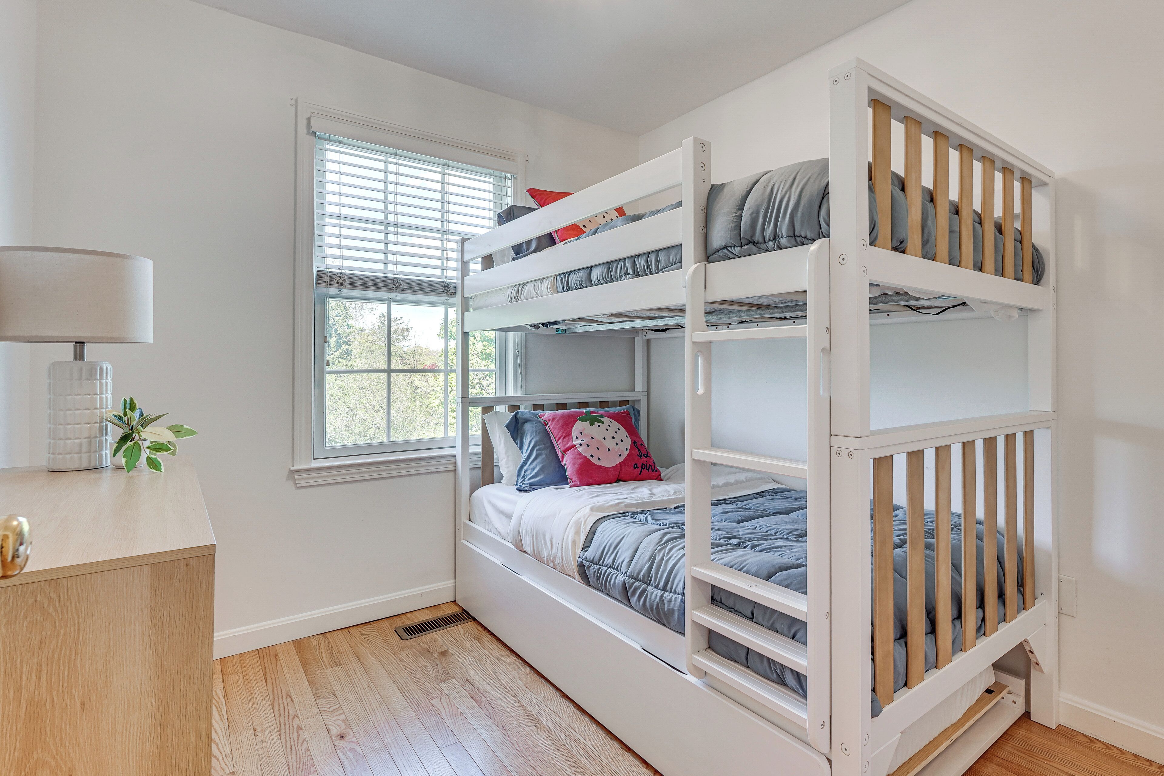 A bunk bed with a desk and window in a room.