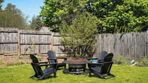 A backyard with a wooden fence, a fire pit, and three Adirondack chairs. - 4 Mi to Beach & Dtwn! Charming Fairfield Home (Fairfield)