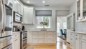 A modern kitchen with white cabinetry, stainless steel appliances, and a large window with a view. - 4 Mi to Beach & Dtwn! Charming Fairfield Home (Fairfield)