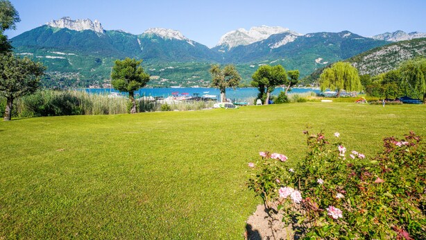 Un campo cubierto de hierba con un lago y montañas al fondo.