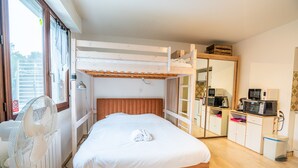 Habitación con literas, un ventilador, un espejo y una kitchenette.
