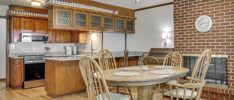 A kitchen with wooden cabinets, a built-in microwave, and a dining area with a round table and chairs.