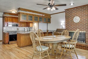 A kitchen with wooden cabinets, a built-in microwave, and a dining area with a round table and chairs. - Fenced Yard & Patio! Shawnee Getaway 2 Mi to Dtwn (Shawnee)