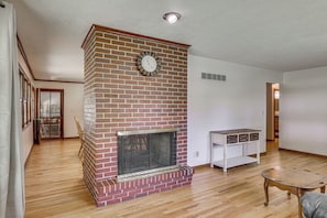 A living room with a brick fireplace, wooden flooring, and a white entertainment unit. - Fenced Yard & Patio! Shawnee Getaway 2 Mi to Dtwn (Shawnee)