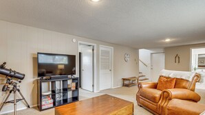Ein Wohnzimmer mit Fernseher, Teleskop, Couchtisch aus Holz und Ledersofa.
