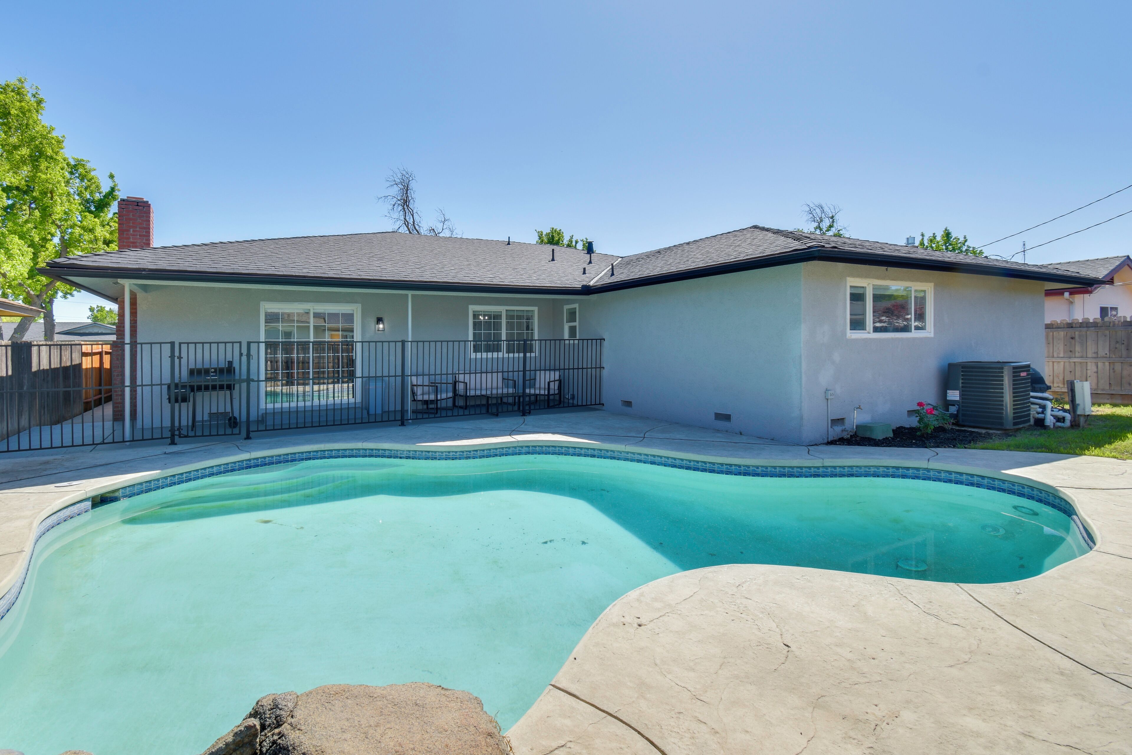 Uma casa com piscina, um pátio cercado e uma pequena garagem anexa.